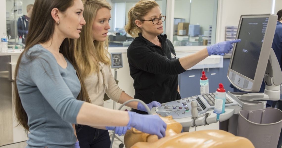 Three students learning how to use an ultrasound machine
